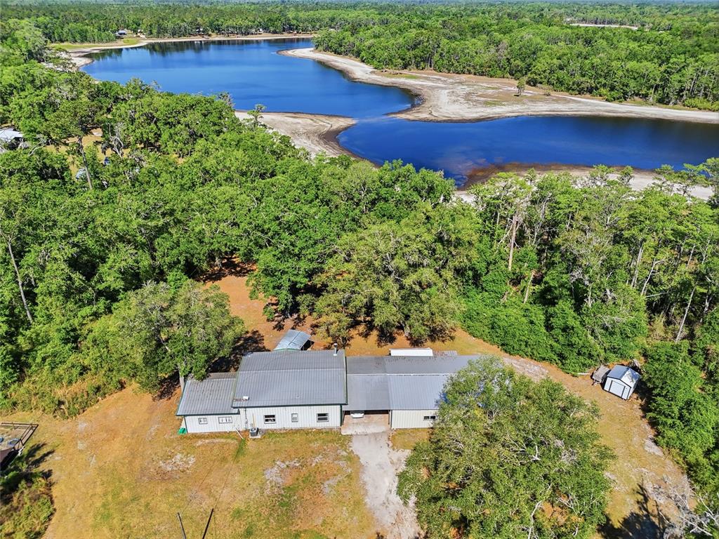 An aerial view shows a house with a metal roof situated near a large lake — 401 SE FALCON ROAD, BRANFORD, FL