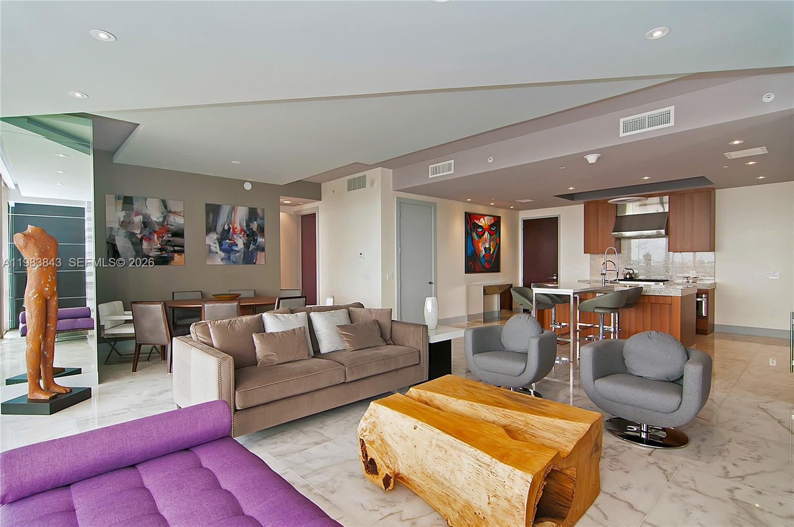 A modern open-concept living room features a purple sofa, wood coffee table, and kitchen — 9705 Collins Ave # 505N, Bal Harbour FL 33154, BAL HARBOUR, FL