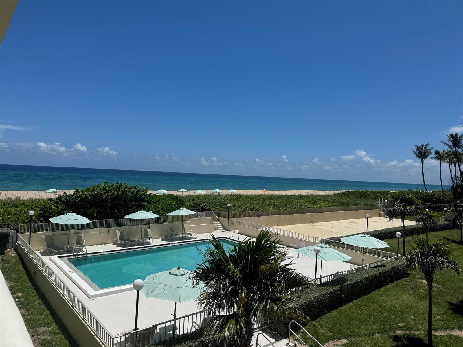 An elevated view of a swimming pool with umbrellas, a beach, and the ocean beyond — 2545 S Ocean Boulevard # 3140, Palm Beach FL 33480, PALM BEACH, FL