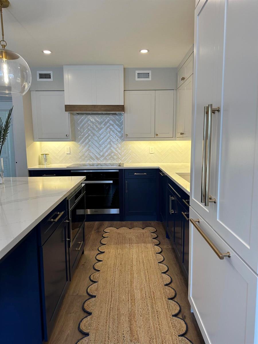 A kitchen features navy blue lower cabinets, white upper cabinets, a herringbone backsplash, and gold hardware — 2545 S Ocean Boulevard # 3140, Palm Beach FL 33480, PALM BEACH, FL