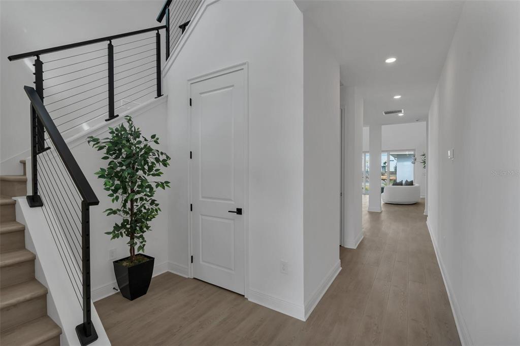 An entryway features a staircase with cable railings, light wood flooring, and a white door — 9823 PEEBLES STREET, ORLANDO, FL