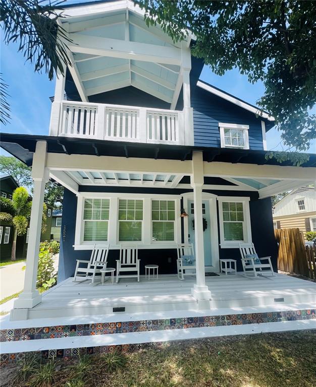 A two-story blue house features a front porch with rocking chairs and decorative tile trim — 1521 E HARWOOD STREET, ORLANDO, FL