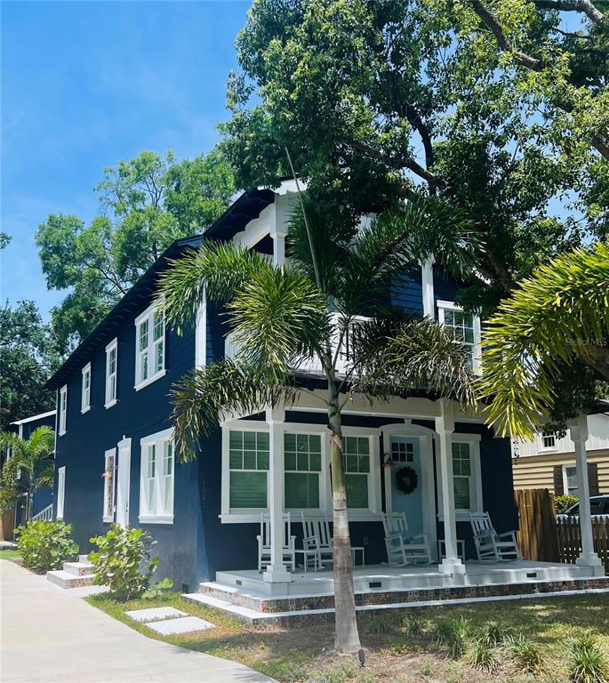 A two-story dark blue house features a front porch with rocking chairs and a palm tree — 1521 E HARWOOD STREET, ORLANDO, FL