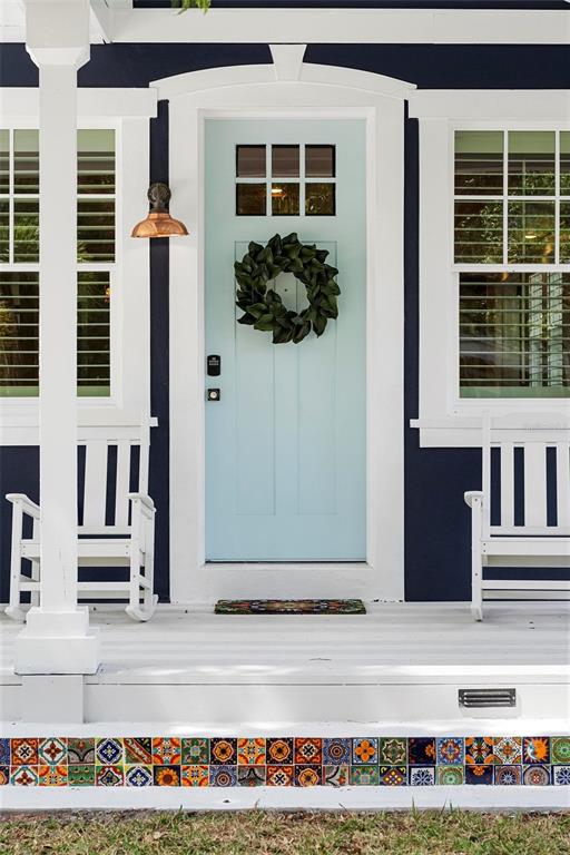 A front porch features a light blue door, white rocking chairs, and decorative tile risers — 1521 E HARWOOD STREET, ORLANDO, FL
