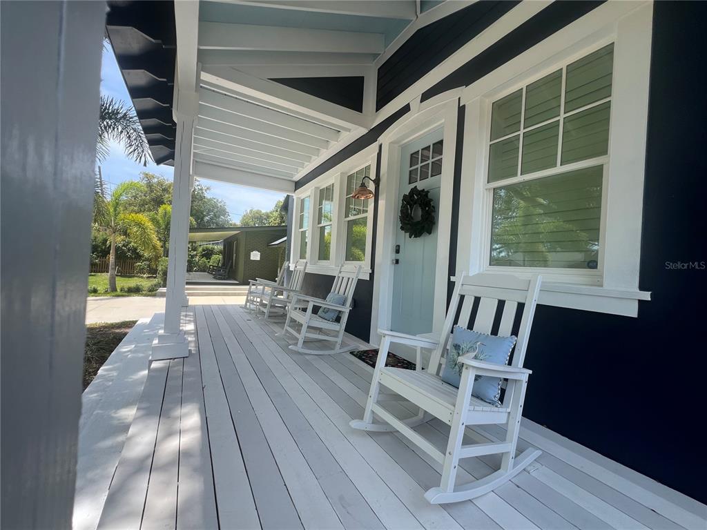 A covered front porch features white rocking chairs, a light blue door, and dark siding — 1521 E HARWOOD STREET, ORLANDO, FL