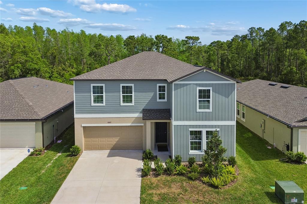An aerial view of a two-story house with blue siding, a tan garage, and landscaping — 10065 GENTLE RAIN DRIVE, LAND O LAKES, FL