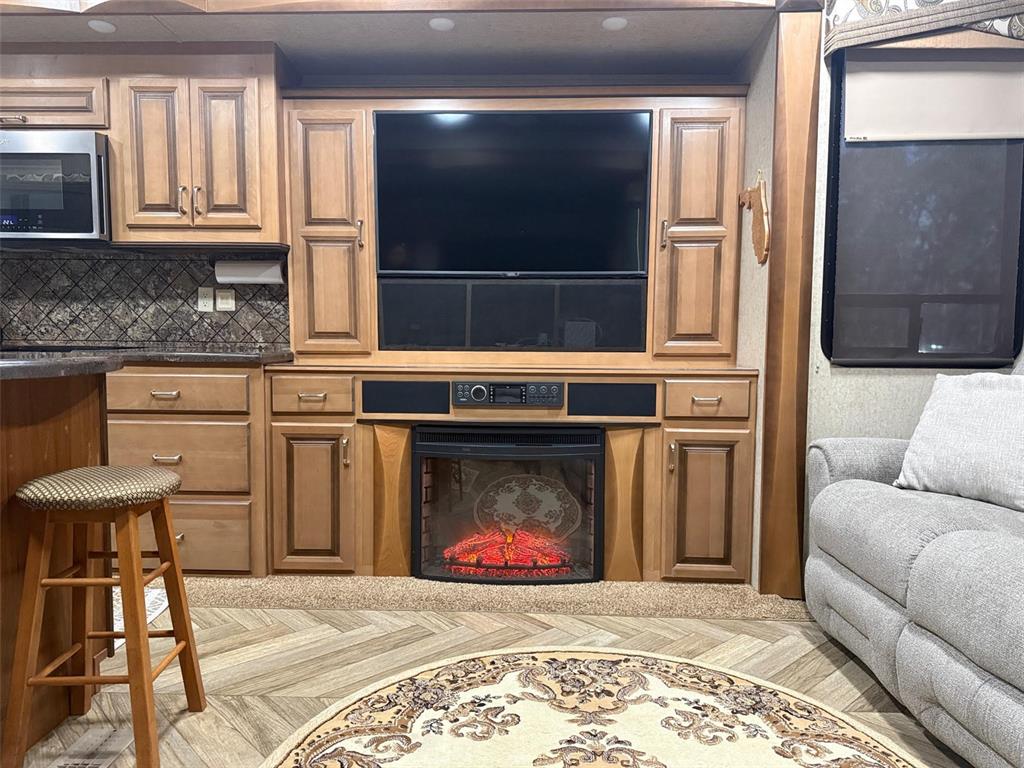 A living area features a built-in entertainment center with a television, fireplace, and wooden cabinetry — 9265 GRIZZLY BEAR LANE, WEEKI WACHEE, FL