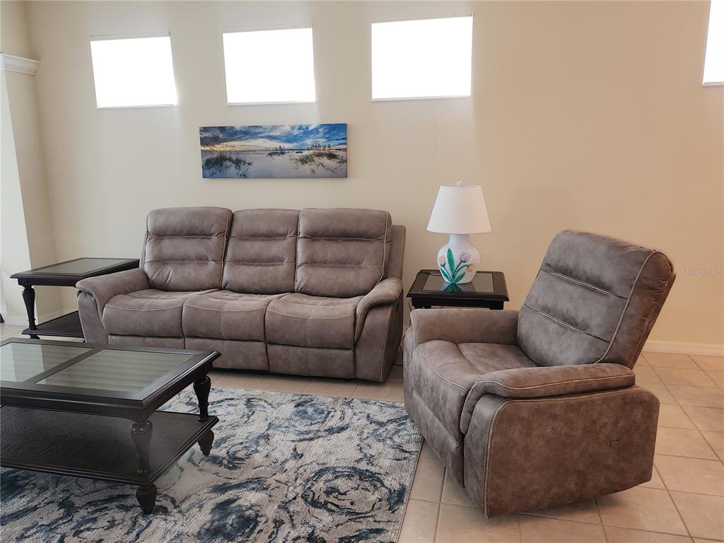 A living room features a gray reclining sofa, a matching armchair, and a coffee table — 6642 TAILFEATHER WAY, BRADENTON, FL