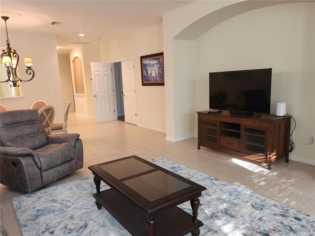 A living room features a television on a wooden stand, a recliner, and a coffee table — 6642 TAILFEATHER WAY, BRADENTON, FL