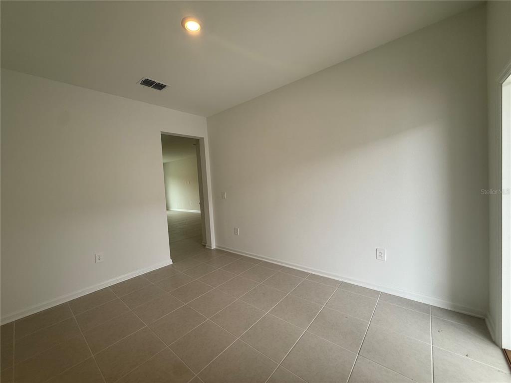 This room features light-colored tile flooring, white walls, and a doorway leading to another area — 3061 CHROMATIC STREET, KISSIMMEE, FL
