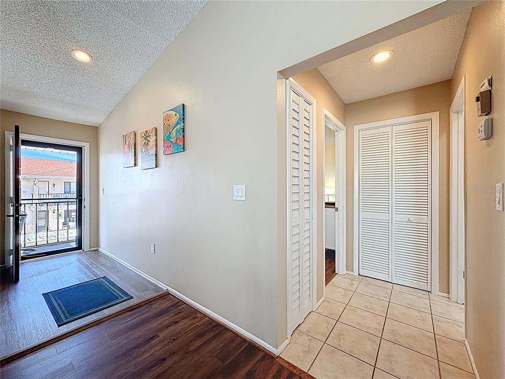 An entryway features wood-look flooring, a tiled hallway, louvered closet doors, and wall art — 9961 EAGLES POINT CIRCLE UNIT 4, PORT RICHEY, FL