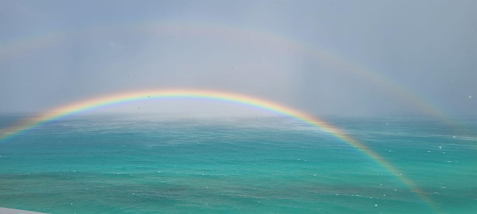 A vibrant double rainbow arches over the turquoise ocean water viewed from a high vantage — 9960 S Ocean Drive # 1402, Jensen Beach FL 34957, JENSEN BEACH, FL