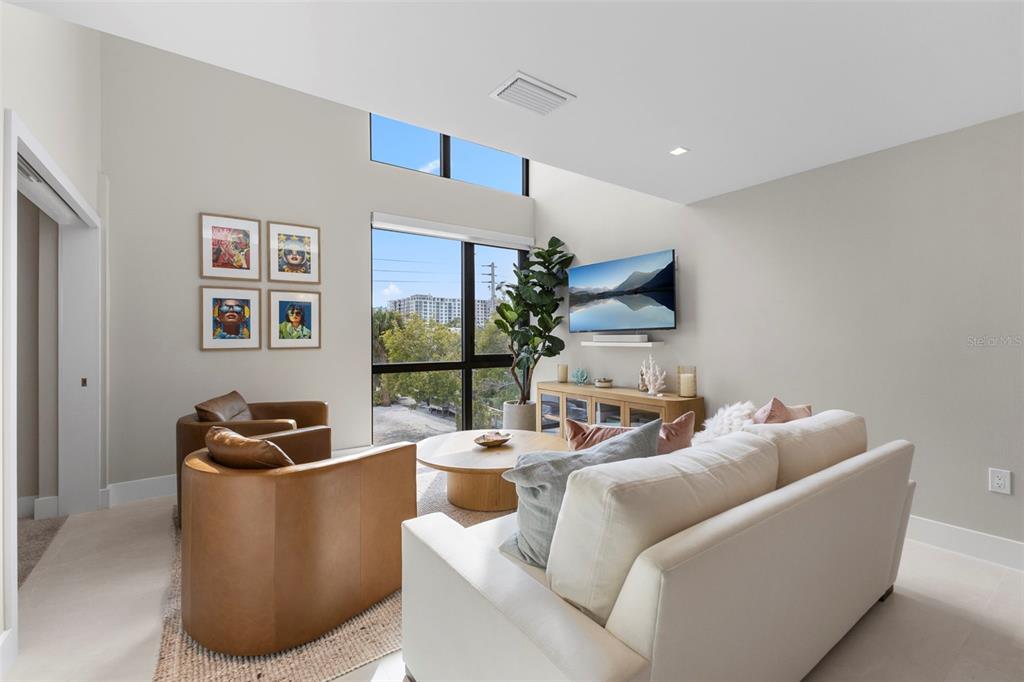 A living room features a white sofa, two leather chairs, a coffee table, and large windows — 1558 4TH ST UNIT 212, SARASOTA, FL