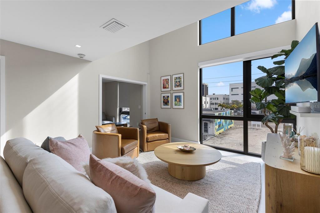 A modern living room features a sofa, two leather chairs, a round table, and floor-to-ceiling windows — 1558 4TH ST UNIT 212, SARASOTA, FL