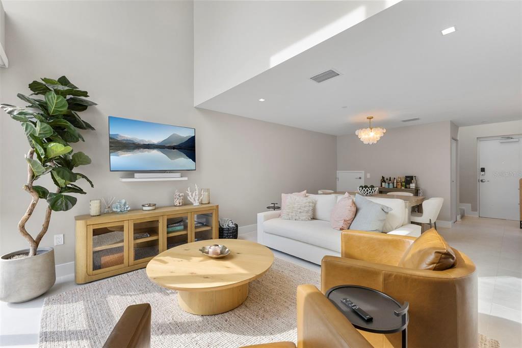 A living room features a white sofa, two leather armchairs, a wooden coffee table, and television — 1558 4TH ST UNIT 212, SARASOTA, FL
