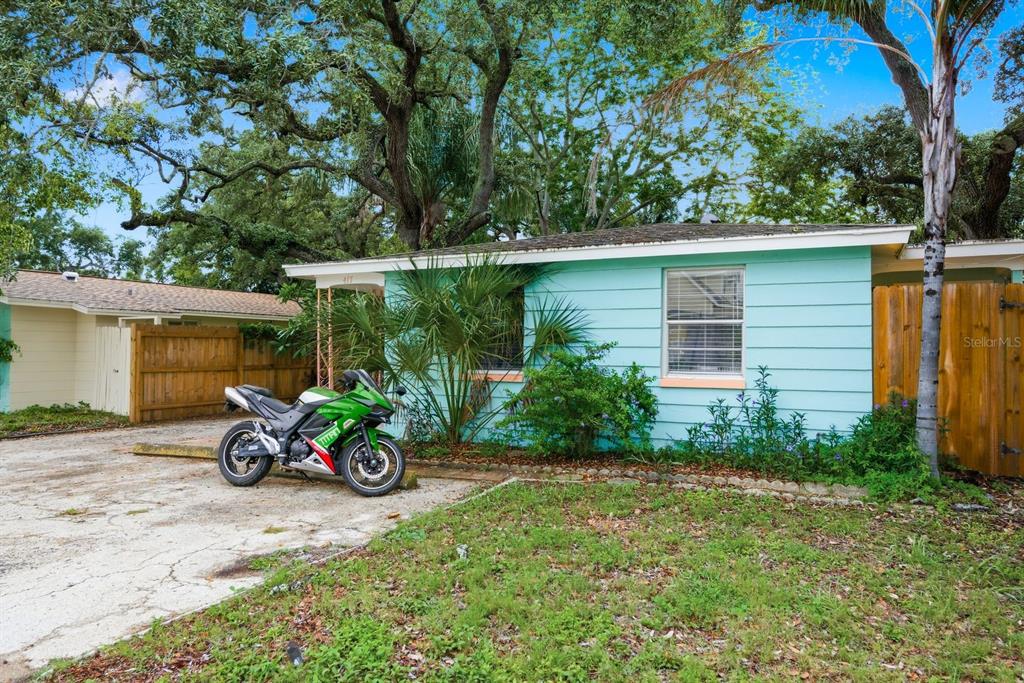 A light blue house with a green motorcycle parked on the concrete driveway — 417 MILWAUKEE AVENUE, DUNEDIN, FL