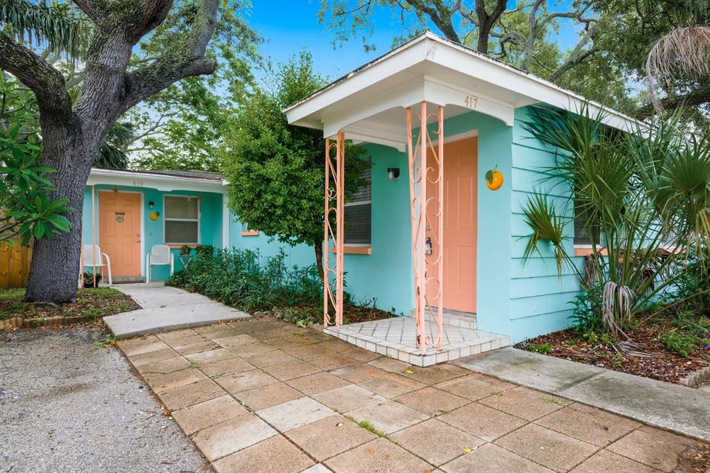 Two turquoise cottages with peach-colored doors and decorative metal porch supports sit on a lot — 417 MILWAUKEE AVENUE, DUNEDIN, FL