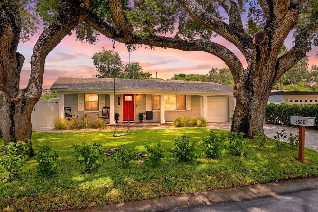 A single-story house with a red front door, a tree swing, and large oak trees — 5580 TANGELO ROAD, SEMINOLE, FL