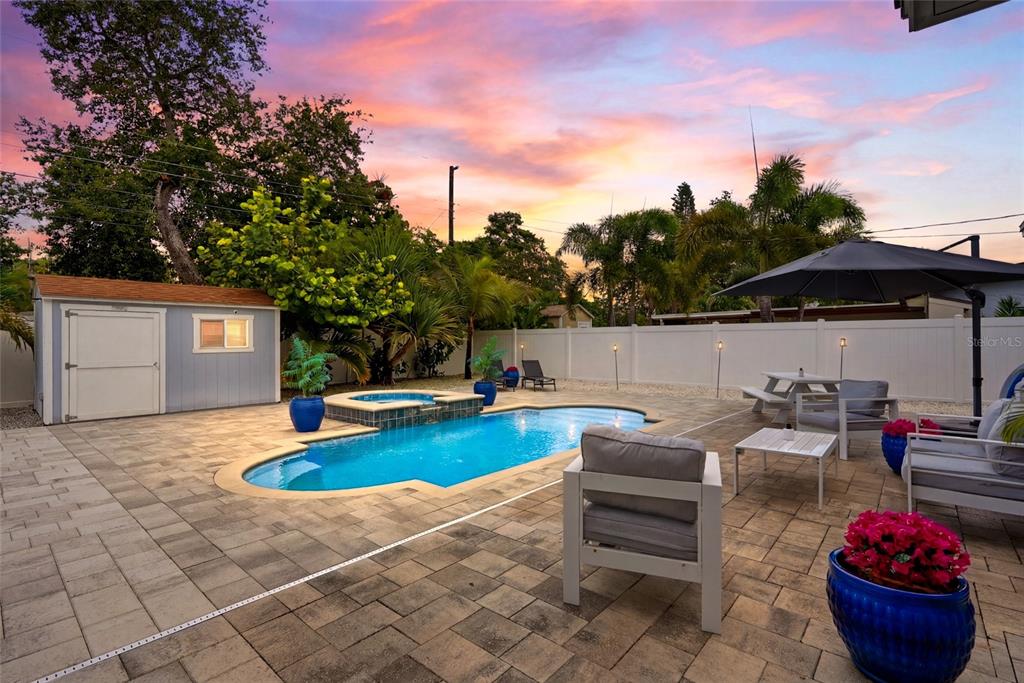 A backyard features a swimming pool with a spa, patio furniture, and a storage shed — 5580 TANGELO ROAD, SEMINOLE, FL