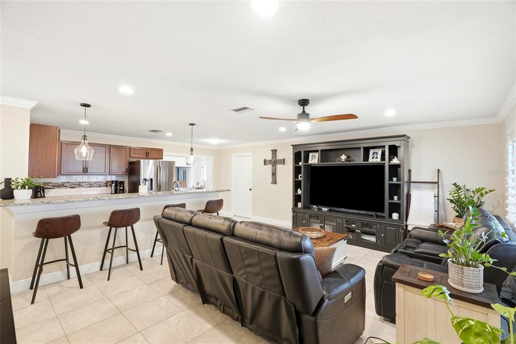 A living room with a kitchen island, dark leather furniture, and a large media center — 5580 TANGELO ROAD, SEMINOLE, FL