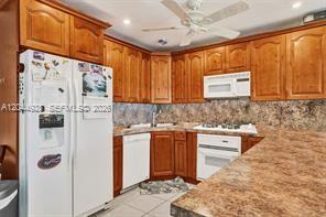 A kitchen features wood cabinets, a white refrigerator, a stove, and a patterned countertop — 1061 NE 26th Ave # 1061, Pompano Beach FL 33062, POMPANO BEACH, FL