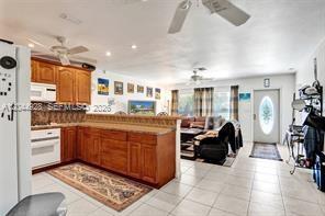 A kitchen with wood cabinets and a breakfast bar opens into a living area — 1061 NE 26th Ave # 1061, Pompano Beach FL 33062, POMPANO BEACH, FL