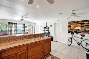 A kitchen with wood cabinets and a breakfast bar overlooks a room with a bicycle — 1061 NE 26th Ave # 1061, Pompano Beach FL 33062, POMPANO BEACH, FL