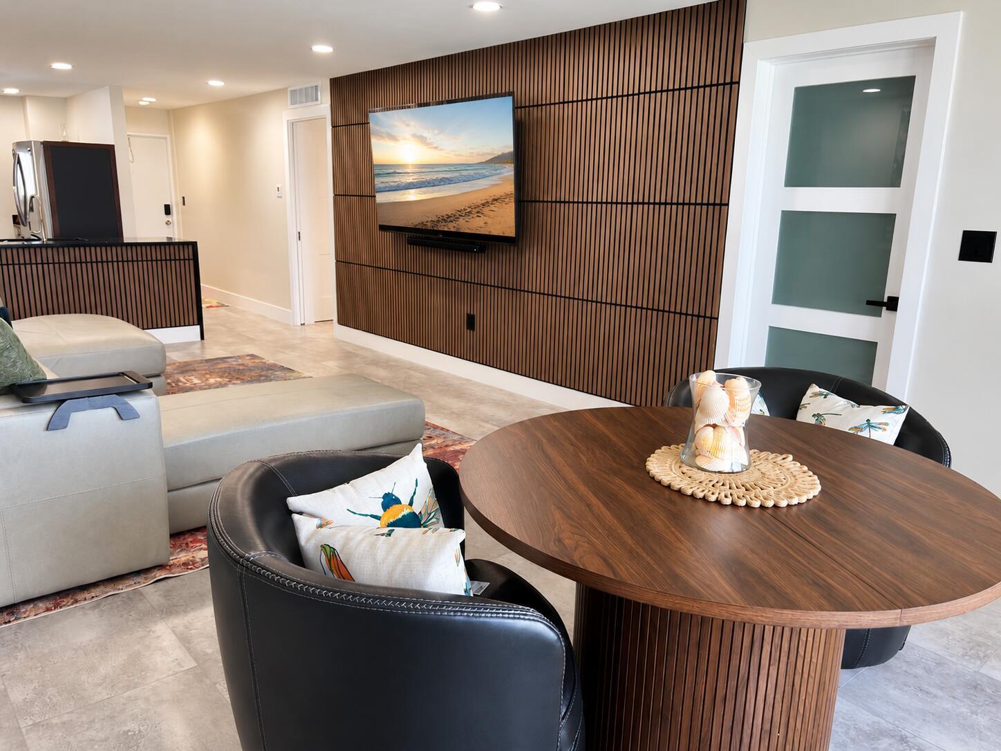 A living and dining area features a slatted wood accent wall and a round table — 9940 S Ocean Drive # 802, Jensen Beach FL 34957, JENSEN BEACH, FL