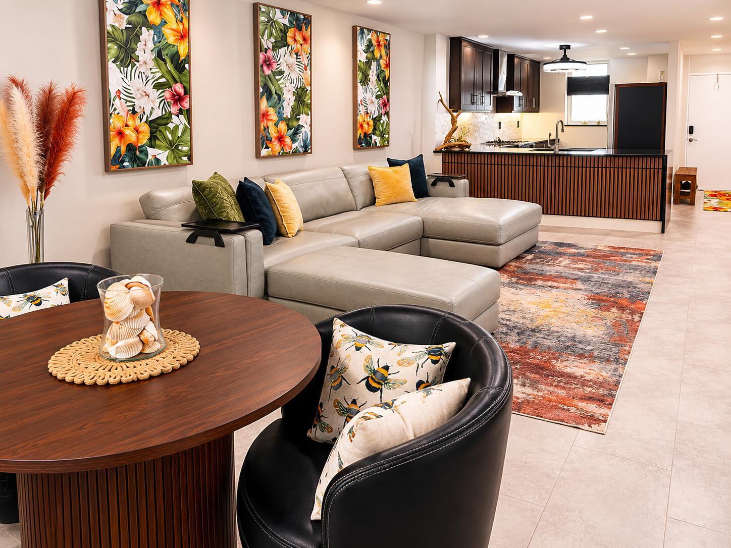An open-concept living room and kitchen feature a grey sectional, dining area, and dark cabinetry — 9940 S Ocean Drive # 802, Jensen Beach FL 34957, JENSEN BEACH, FL