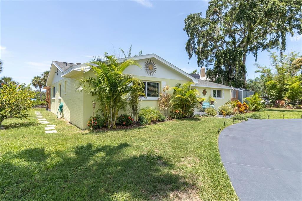 A light yellow, single-story house with a palm-lined front yard and a curved driveway — 7213 PENINSULAR DRIVE, NEW PORT RICHEY, FL
