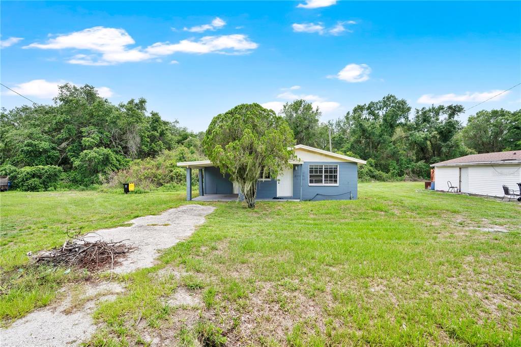 A blue single-story house with a front porch sits on a large, grassy lot — 255 HOOKER STREET, MULBERRY, FL