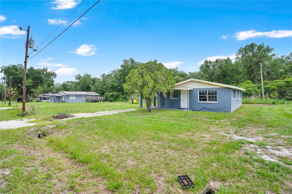 A blue single-story house sits on a large grassy lot with trees in the background — 255 HOOKER STREET, MULBERRY, FL