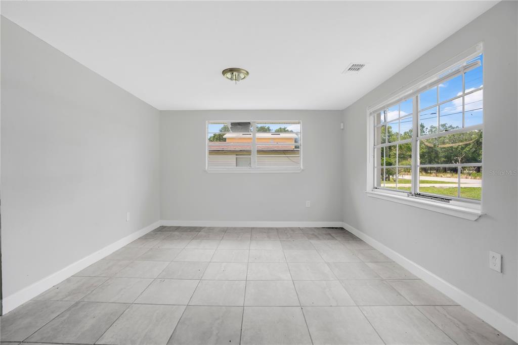 An empty room with light gray walls, large floor tiles, and two windows — 255 HOOKER STREET, MULBERRY, FL