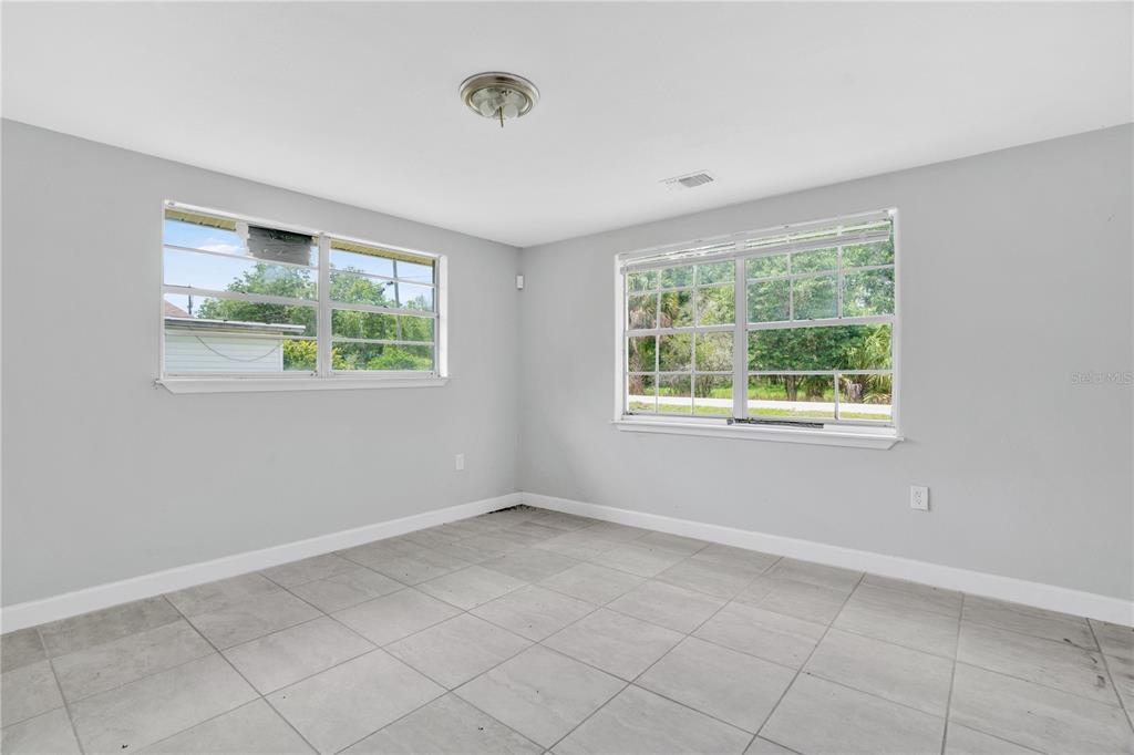 An empty room with light gray walls, large windows, and light-colored tile flooring — 255 HOOKER STREET, MULBERRY, FL