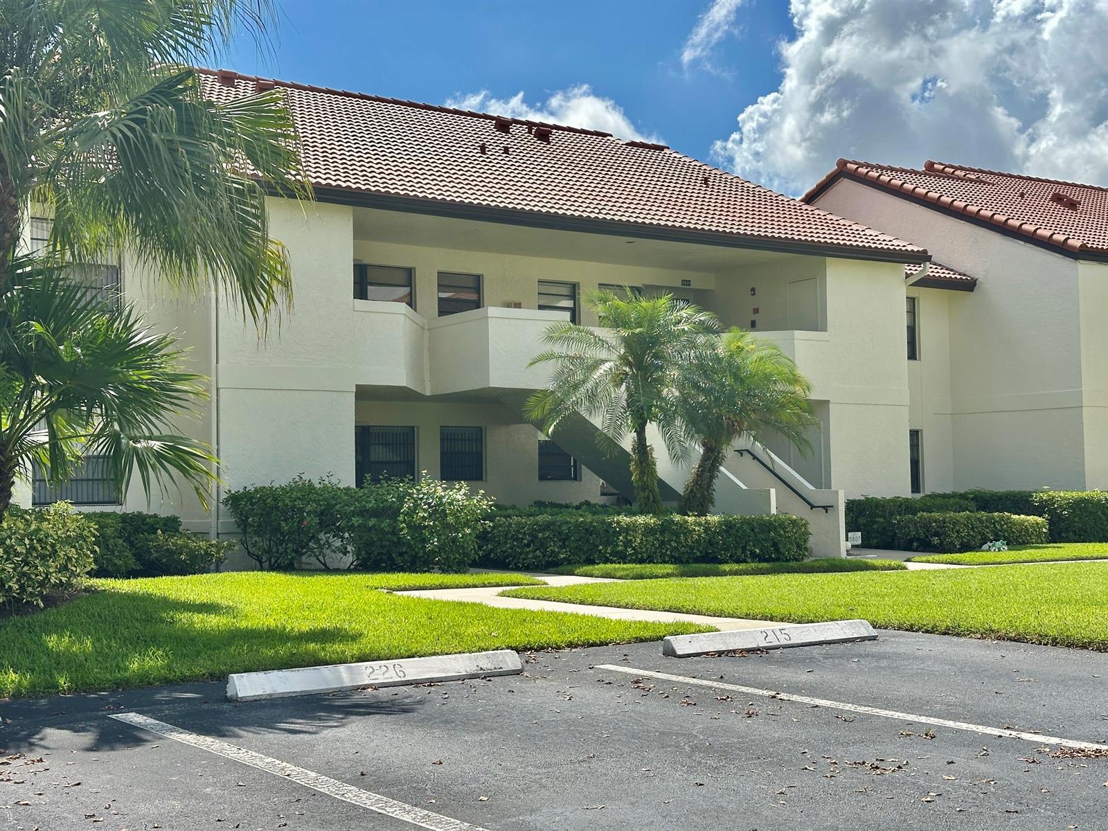 A two-story apartment building with a tiled roof, palm trees, and marked parking spaces — 5807 Parkwalk Drive, Boynton Beach FL 33472, BOYNTON BEACH, FL