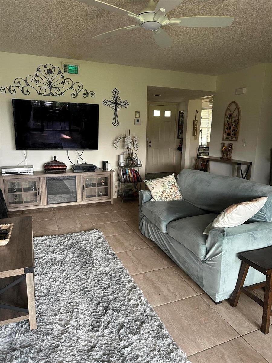 A living room features a television on a media console, a sofa, and tile flooring — 5807 Parkwalk Drive, Boynton Beach FL 33472, BOYNTON BEACH, FL
