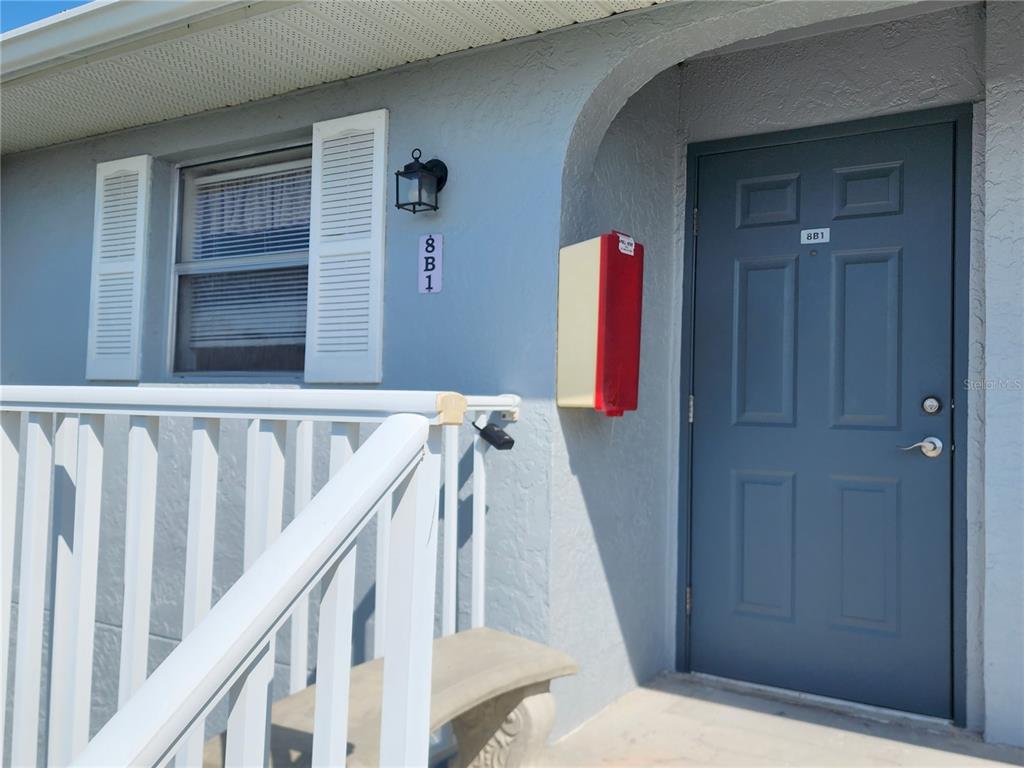 A blue door with the number 8B1 stands next to a window with white shutters — 25050 SANDHILL BOULEVARD UNIT B1, PUNTA GORDA, FL
