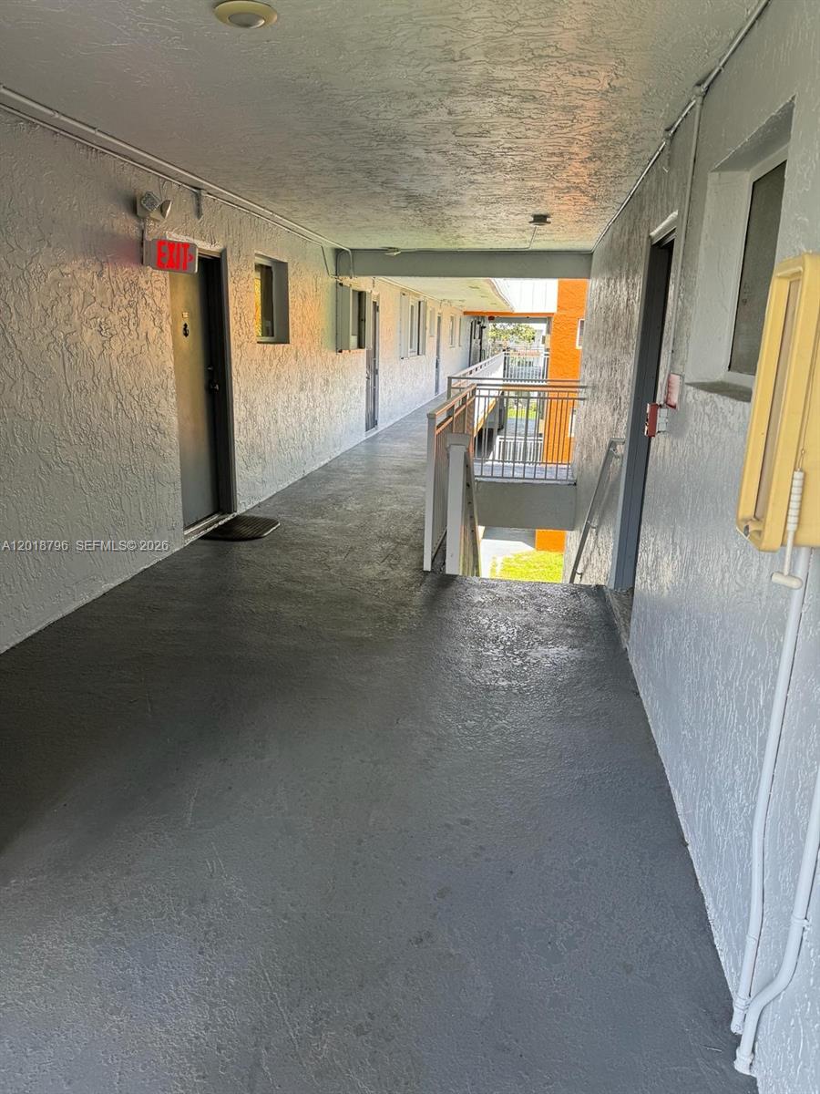An outdoor apartment building walkway features gray painted concrete floors and a metal stairwell — 11307 SW 200th St # B, Miami FL 33157, MIAMI, FL