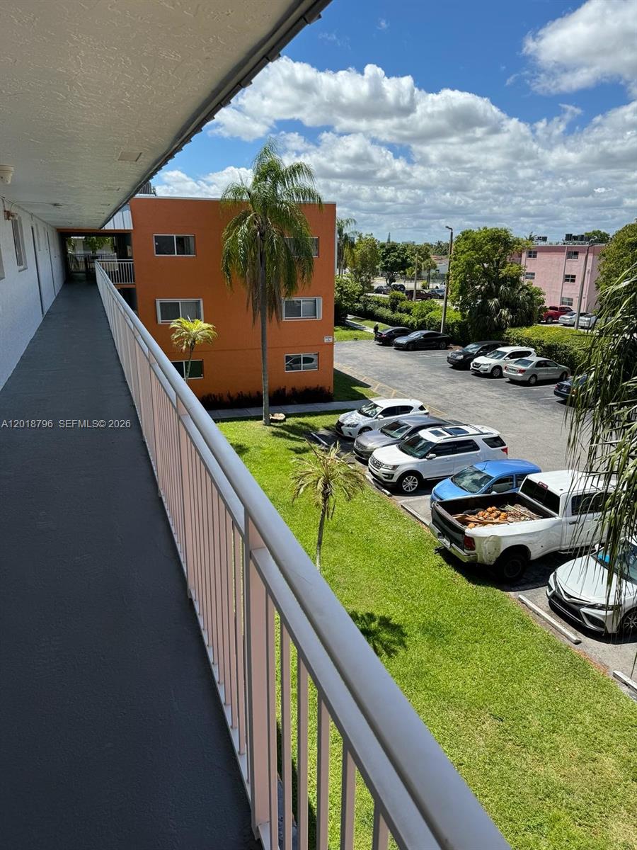 An elevated walkway overlooks a parking lot with several cars and an orange apartment building — 11307 SW 200th St # B, Miami FL 33157, MIAMI, FL
