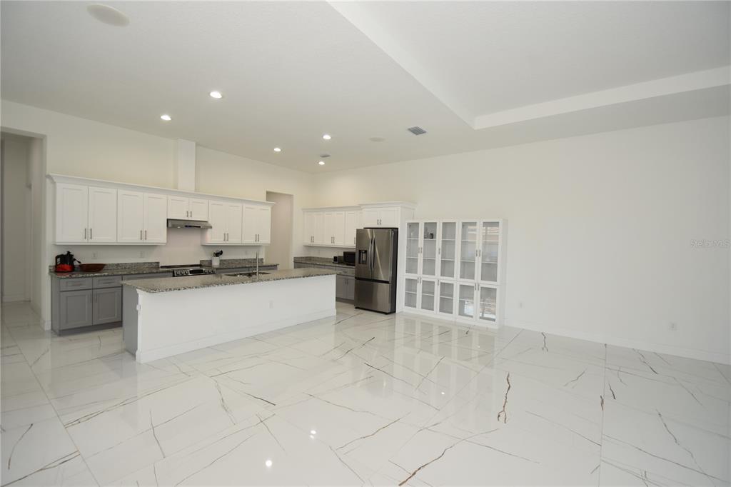 A modern kitchen features white cabinets, gray lower cabinets, granite countertops, and white marble flooring — 108 PLAIN VIEW DRIVE, PALM COAST, FL