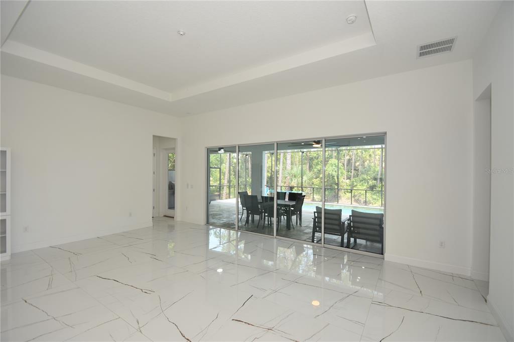 A bright living room features white marble-look tile floors and large sliding glass doors — 108 PLAIN VIEW DRIVE, PALM COAST, FL