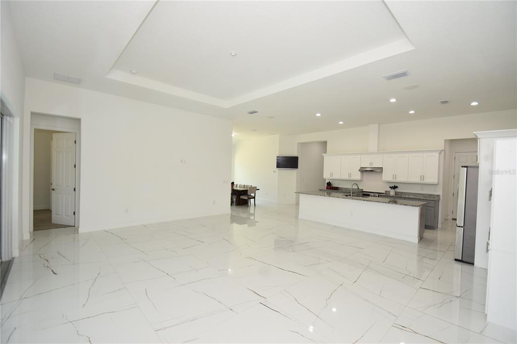 An open-concept living area features white marble-look tile flooring, a tray ceiling, and a kitchen — 108 PLAIN VIEW DRIVE, PALM COAST, FL