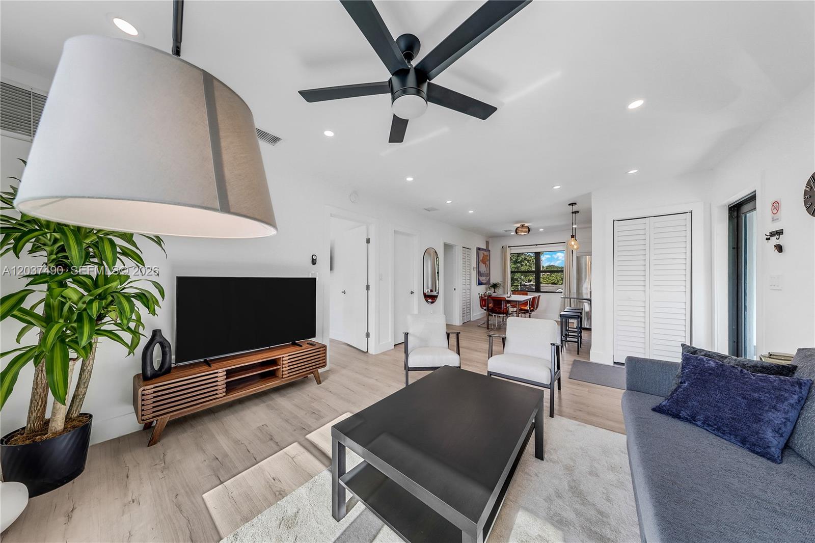 A modern living room features light wood floors, a black ceiling fan, and white walls — 243 NW 32nd St, Miami FL 33127, MIAMI, FL