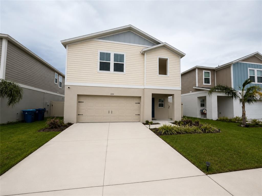 A two-story house with beige siding, a two-car garage, and a concrete driveway — 1352 DERRY AVENUE, HAINES CITY, FL