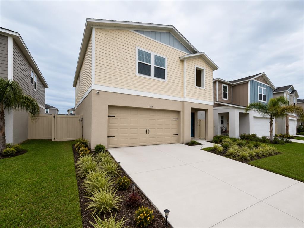 A two-story suburban house features a beige stucco lower level, yellow siding, and a garage — 1352 DERRY AVENUE, HAINES CITY, FL
