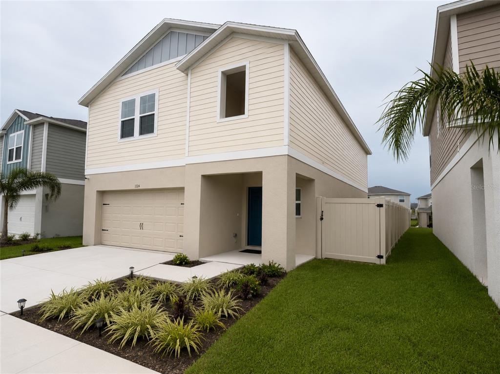 A two-story house with beige siding, a garage, and a white vinyl fence — 1352 DERRY AVENUE, HAINES CITY, FL