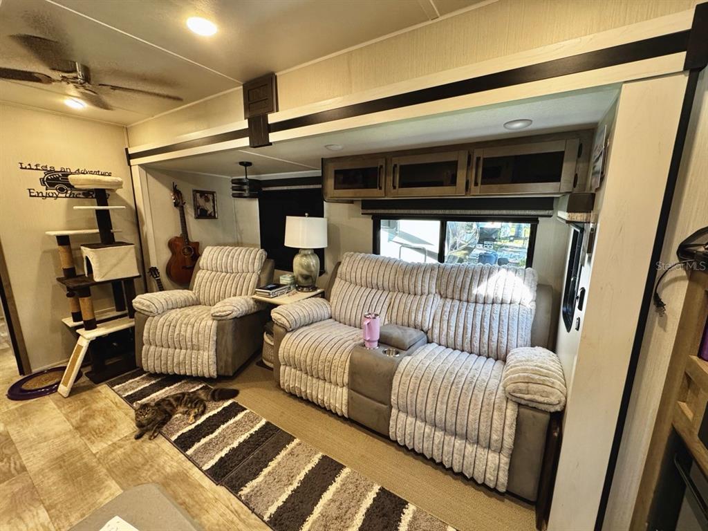 A living area in a recreational vehicle features a sofa, recliner, and a cat tree — 14423 NE 252ND COURT ROAD, SALT SPRINGS, FL