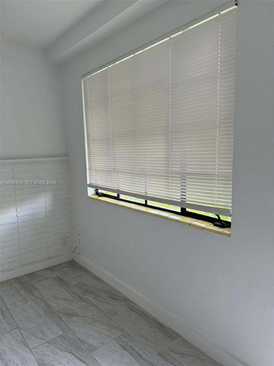 A room features white walls, a tiled floor, a window with blinds, and a brick accent wall — 1324 N 58 AVE, Hollywood FL 33021, HOLLYWOOD, FL