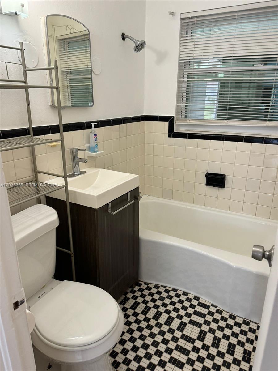A small bathroom features a pedestal sink, a toilet, and a tub with tiled walls — 1324 N 58 AVE, Hollywood FL 33021, HOLLYWOOD, FL