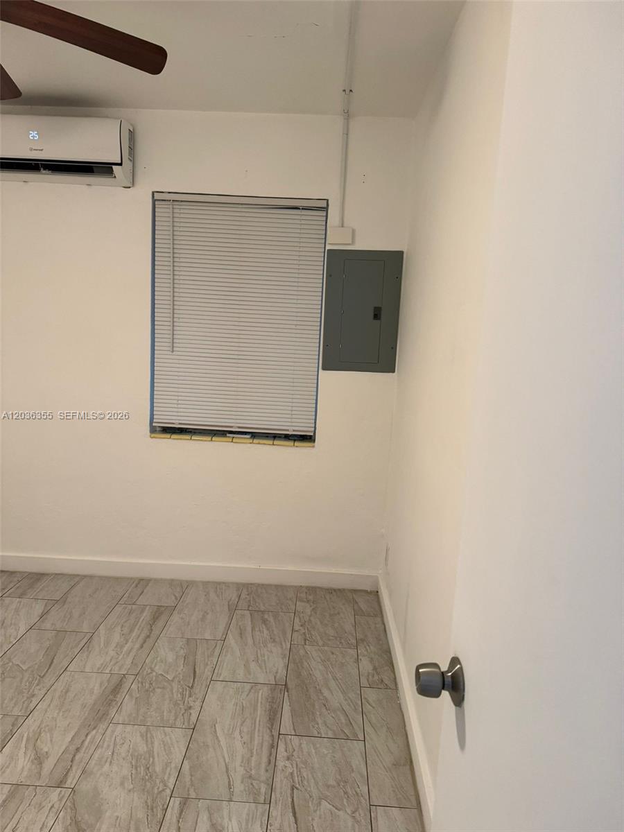 This room features light-colored tile flooring, a window with blinds, a wall-mounted air conditioner, and an electrical panel — 1324 N 58 AVE, Hollywood FL 33021, HOLLYWOOD, FL